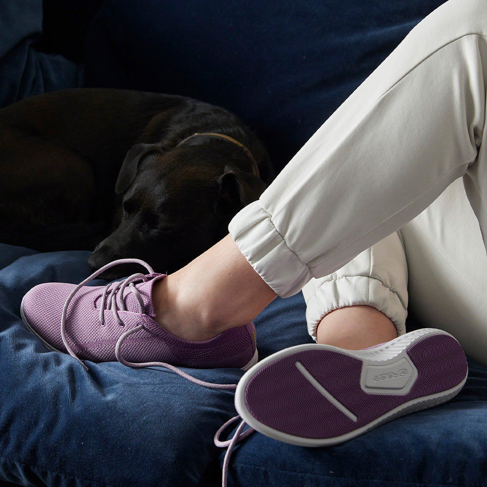 Image of woman wearing greenReActives® footwear on couch with dog